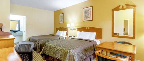 A hotel room with two beds, a desk, a chair, a table, and a mirror.