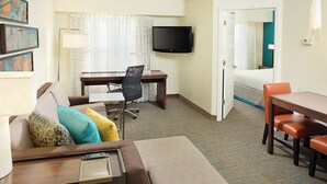 Une chambre d’hôtel comprenant un lit, un bureau avec une chaise, un téléviseur fixé au mur et une table à manger avec des chaises.