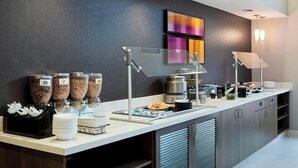 Eine moderne Frühstückstheke mit Selbstbedienungsbehältern für Granola, einer Kaffeemaschine und einer Auswahl an Frühstücksartikeln.