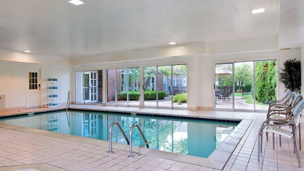 Ein Hallenbad mit großen Glaswänden, gefliestem Boden und Blick ins Freie.
