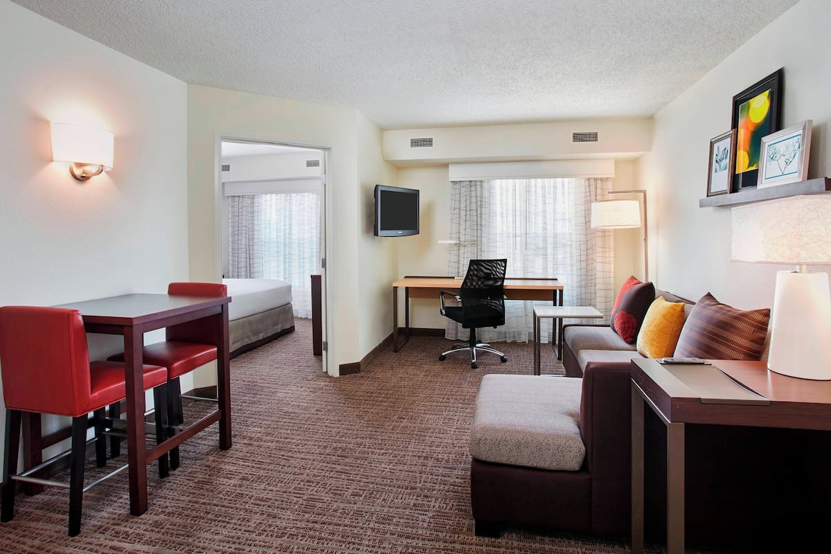 A hotel room with a bed, a desk, a chair, a couch, and a TV.