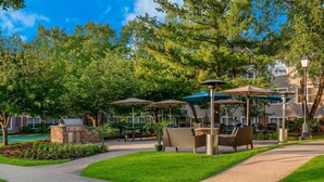 A well-maintained outdoor patio area with seating, umbrellas, and a barbecue grill.