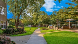 A pathway leading to a patio area with outdoor seating and a building on the left.