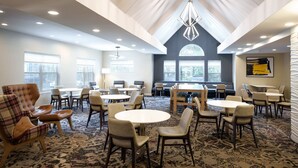 A spacious conference room with multiple tables and chairs, large windows, and a high ceiling with a geometric light fixture. - Residence Inn By Marriott Columbia (Ellicott City)