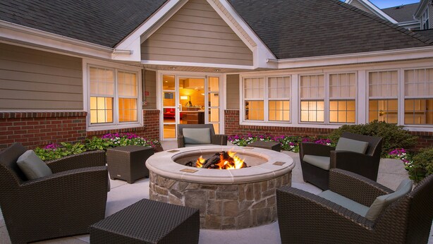 An outdoor patio with a stone fire pit surrounded by wicker furniture. - Residence Inn By Marriott Columbia (Ellicott City)