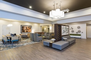 A spacious living area with a modern design, featuring a large sectional sofa, a dining table with chairs, and a fireplace. - Doubletree by Hilton Pleasant Prairie Kenosha (Pleasant Prairie)
