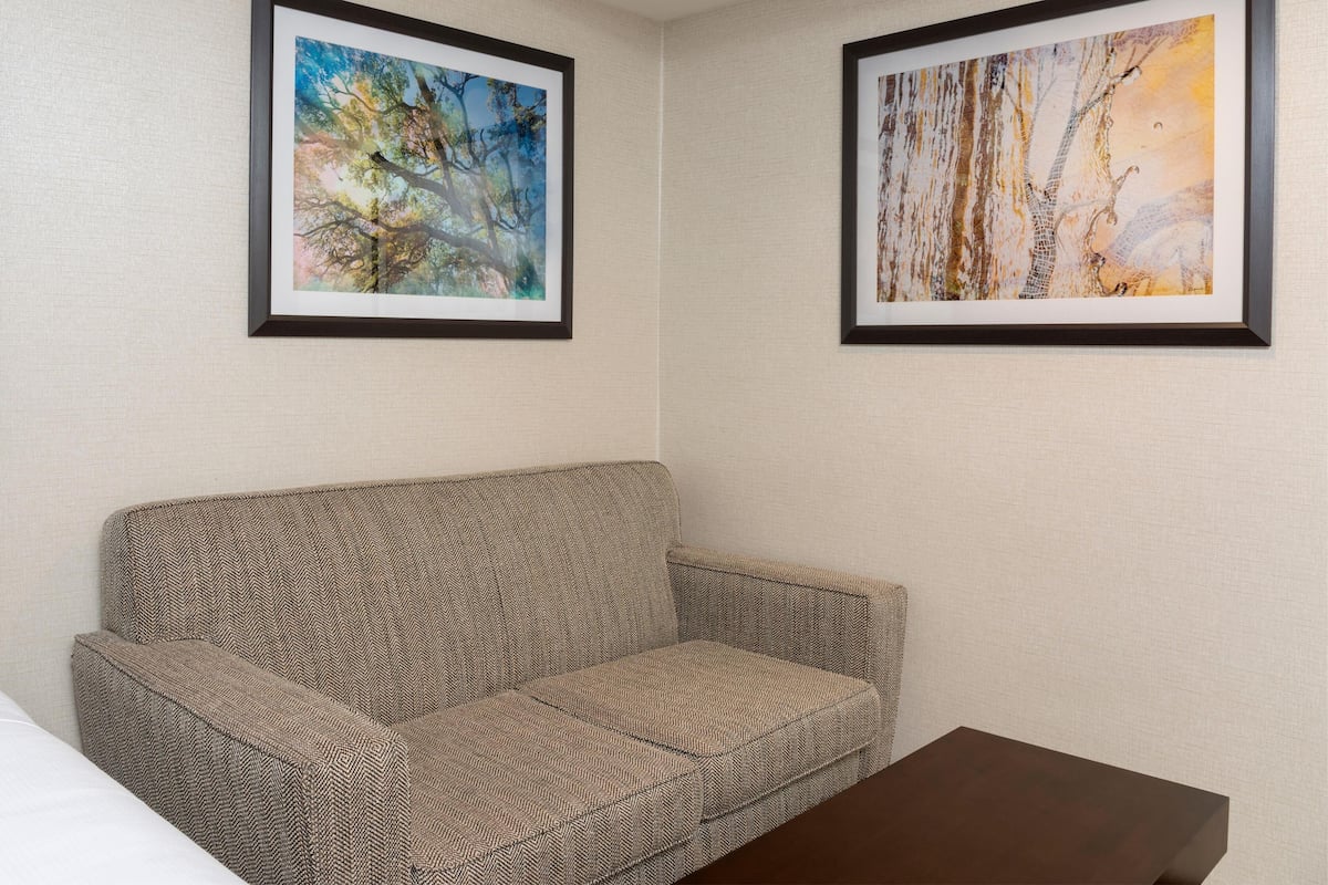 A room with a patterned sofa, two framed artworks on the wall, and a small table.