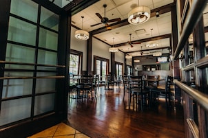 Un amplio interior de restaurante con techos altos, varios ventiladores de techo y diversas opciones de asientos, incluyendo mesas y sillas.