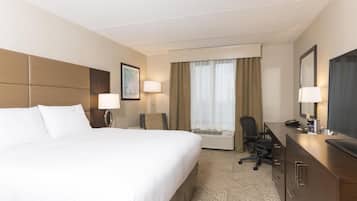 Una habitación de hotel con una cama grande, un escritorio con computadora, una silla y televisión.
