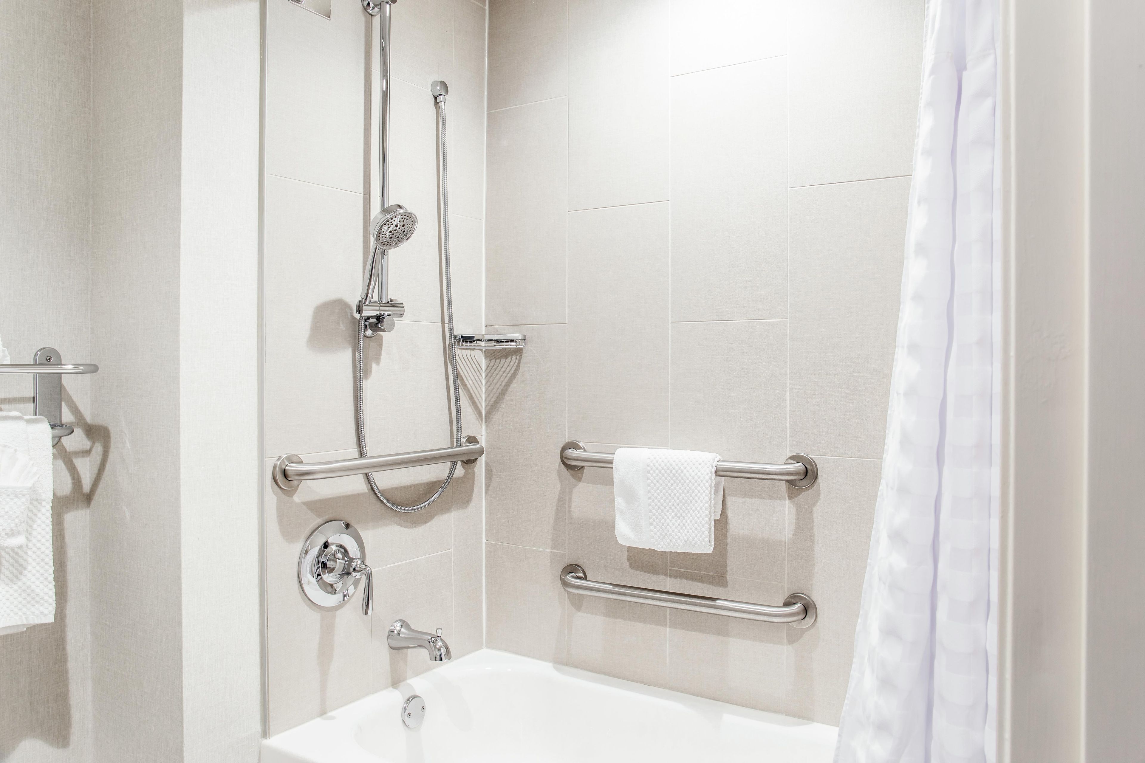 Ein modernes Badezimmer mit Badewanne, Dusche und Haltegriffen.