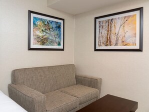 A room with a patterned sofa, two framed artworks on the wall, and a small table. - Doubletree by Hilton Pleasant Prairie Kenosha (Pleasant Prairie)