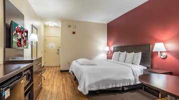 Una habitación de hotel con cama, mesitas de noche, televisor, escritorio y armario.