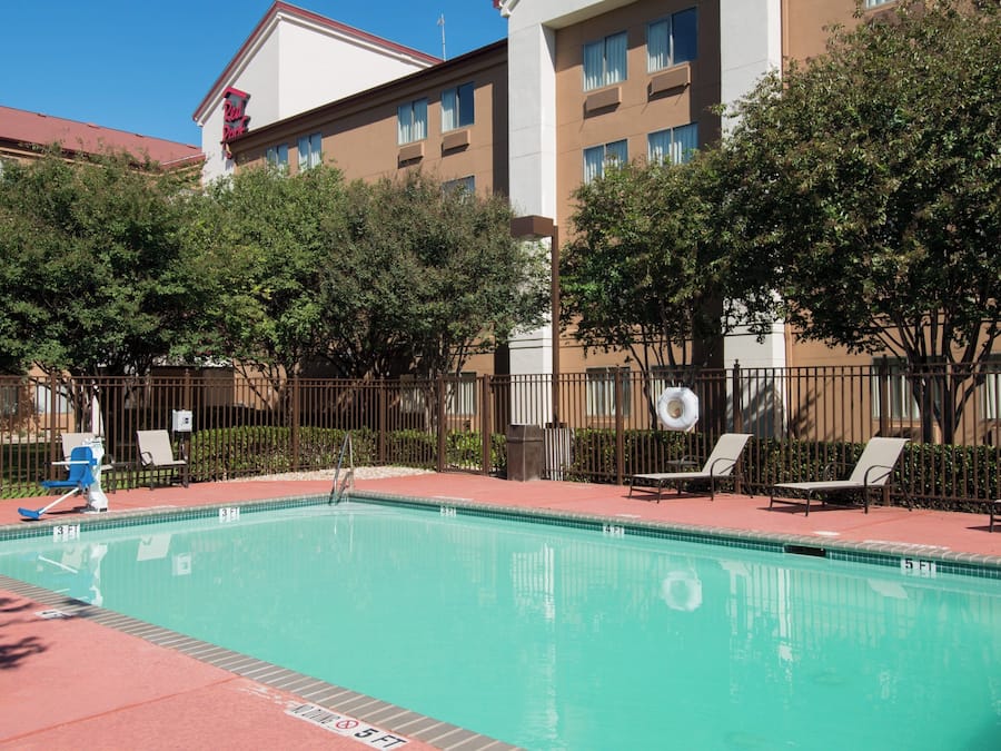 Una piscina al aire libre, sombrillas, sillones reclinables de piscina