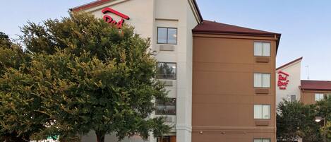 A hotel with a flat facade, multiple windows, and a Red Roof Inn sign.