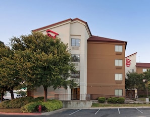 A hotel with a flat facade, multiple windows, and a Red Roof Inn sign. - Red Roof Inn PLUS+ Austin South – Airport. (Austin)
