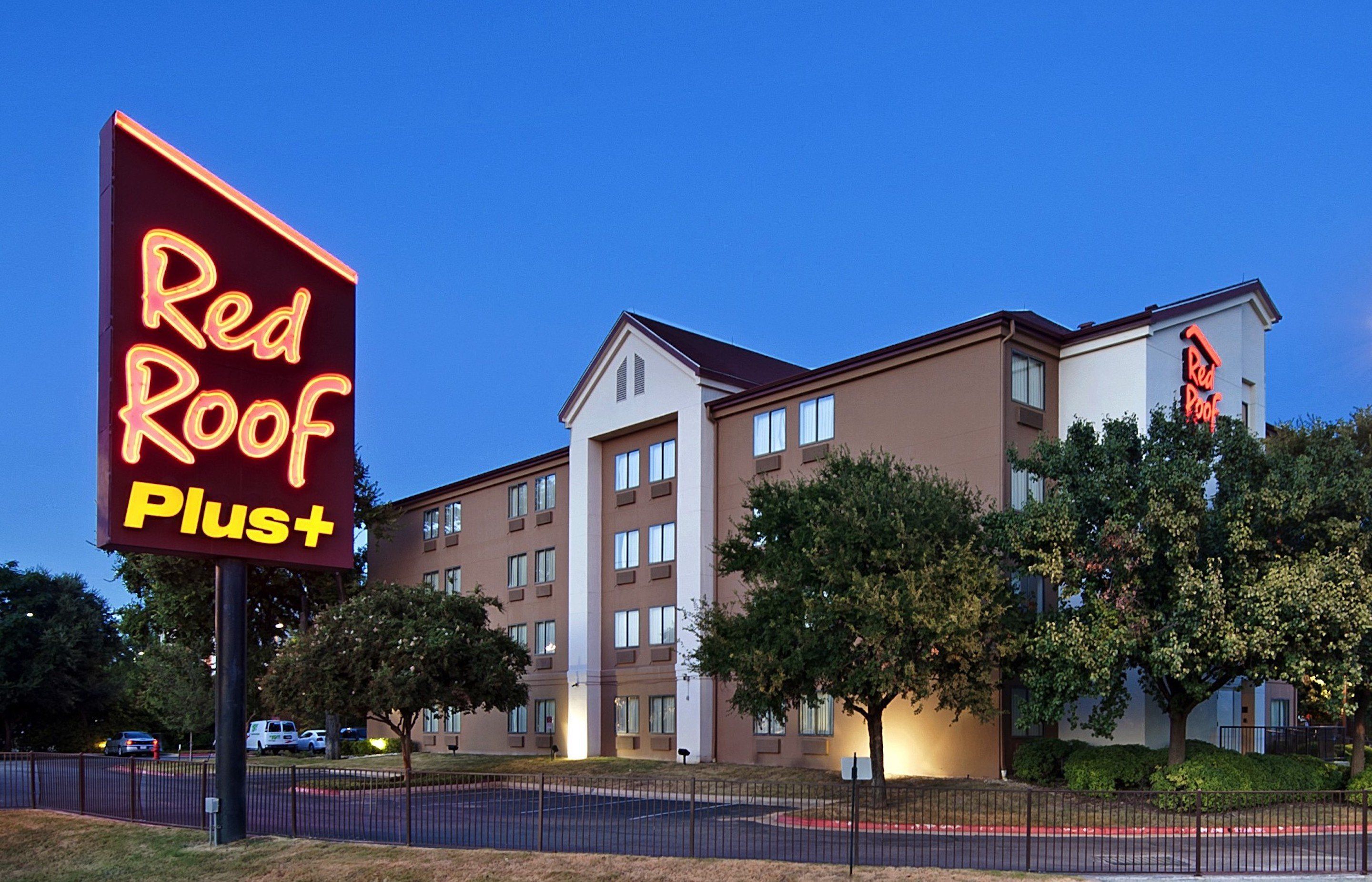 A Red Roof Plus hotel with a modern building facade, multiple windows, and a parking lot.