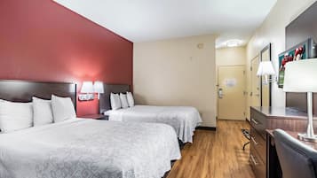 Habitación de hotel con dos camas, un escritorio, un espejo y un televisor.