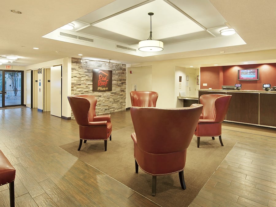 A hotel lobby with leather chairs, a reception desk, and a stone wall.