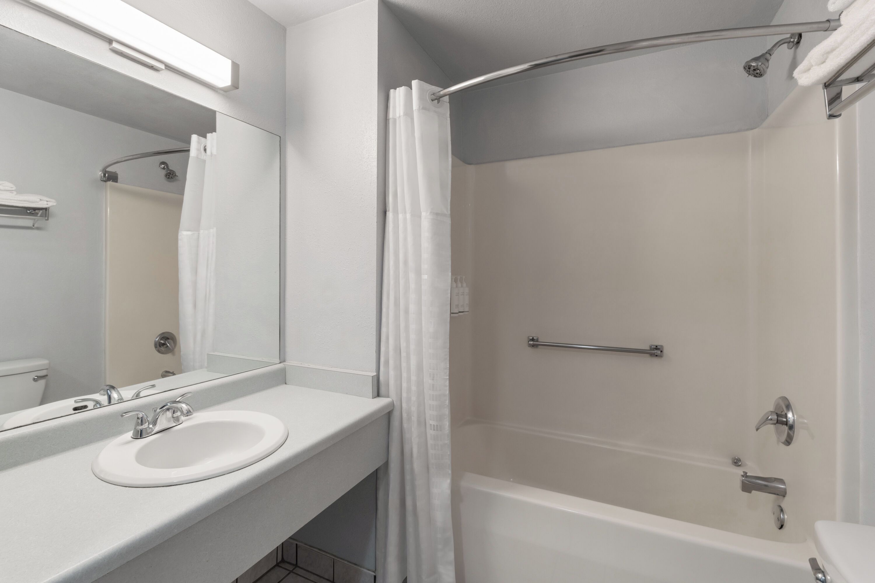 A modern bathroom with a white sink, mirror, and shower area.