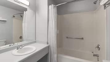 A modern bathroom with a white sink, mirror, and shower area.