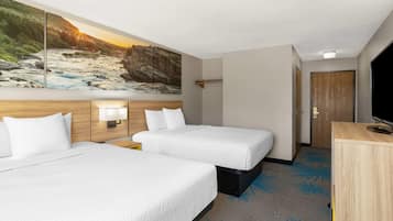A hotel room with two beds, a large painting of a river, a wooden headboard, a nightstand with a lamp, and a TV on a wooden cabinet.