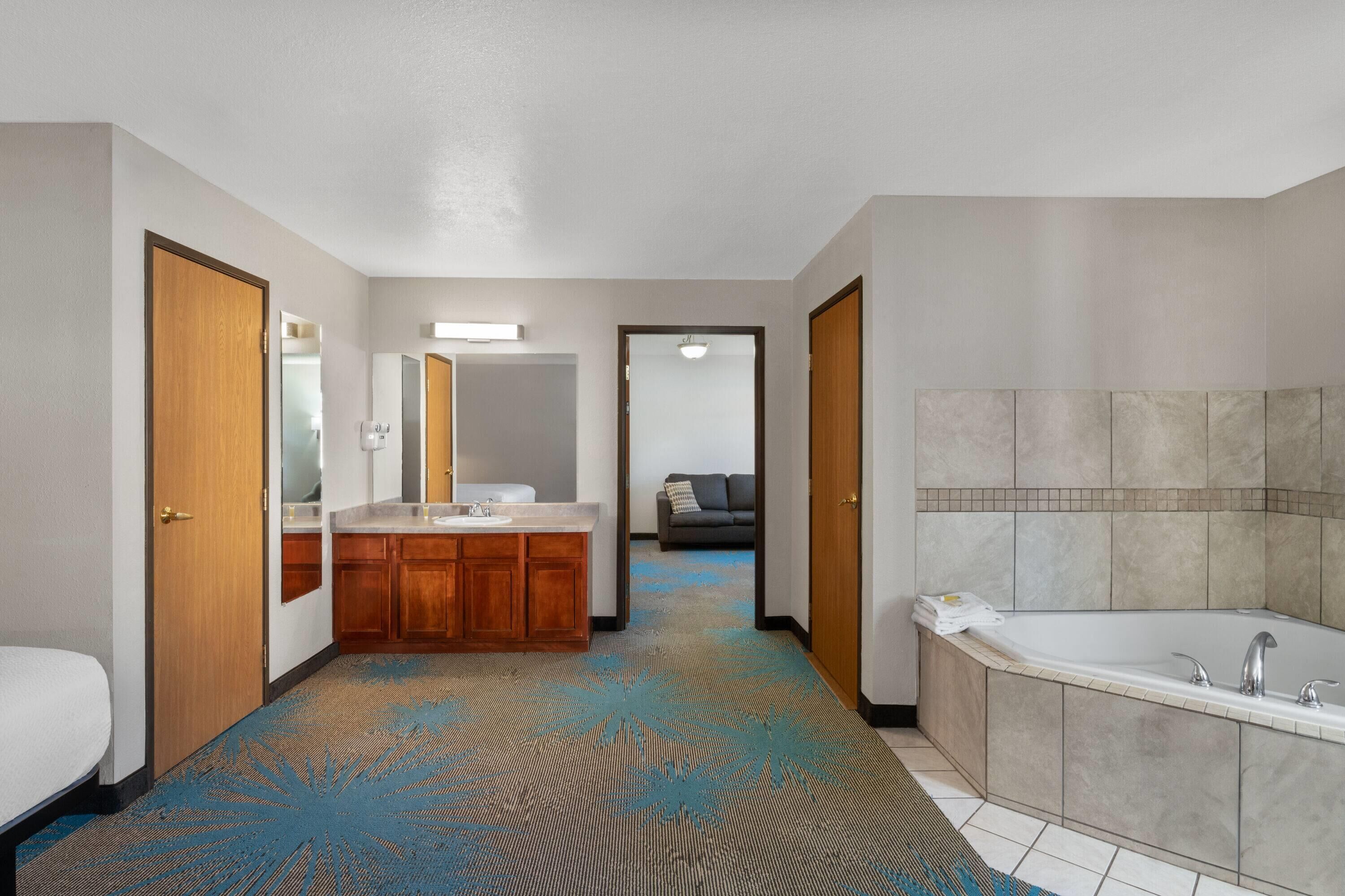 A hotel bathroom with a large bathtub, a double sink vanity, and a mirror.