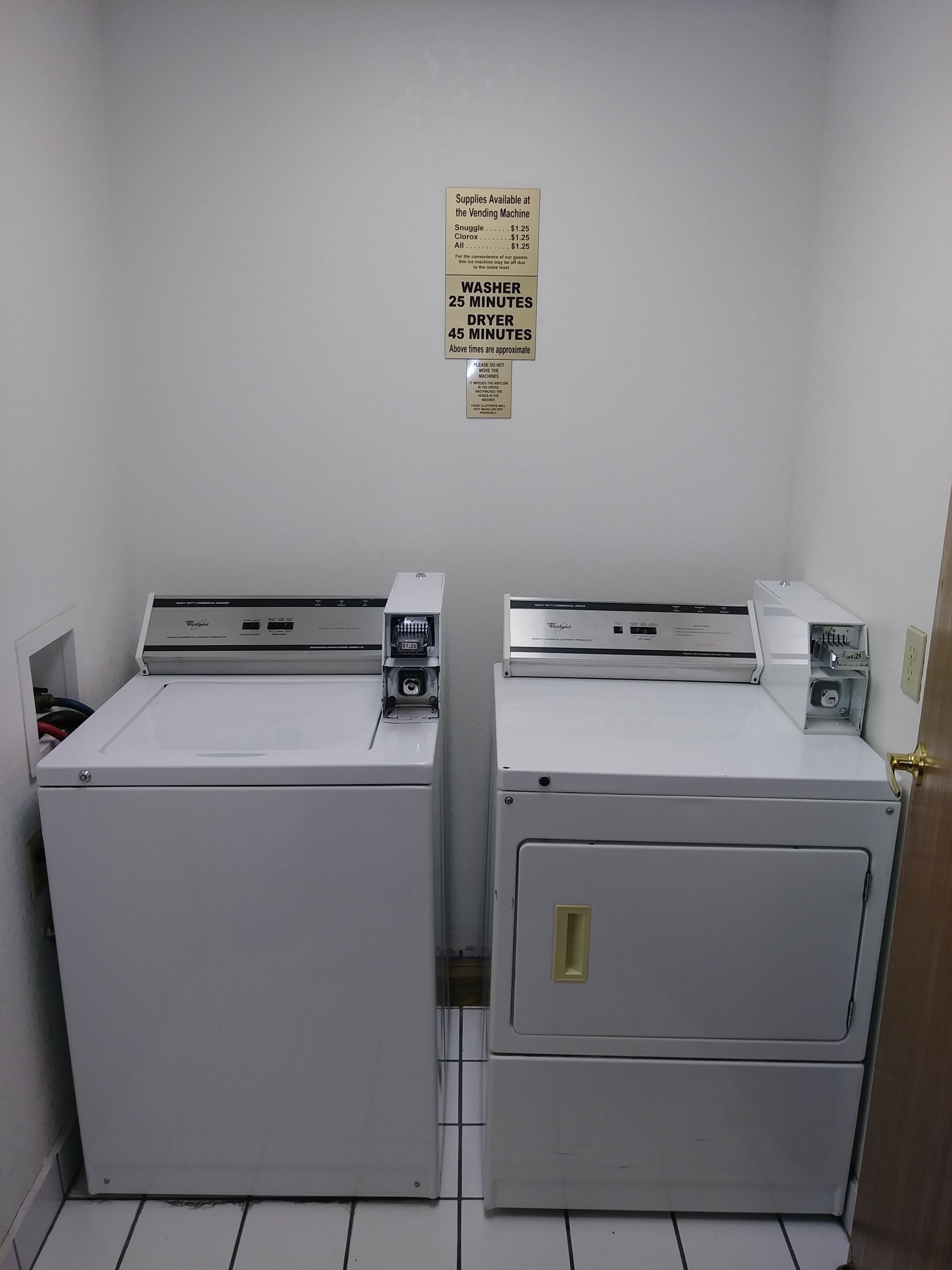 Two white washers and dryers side by side in a room with a tiled floor.