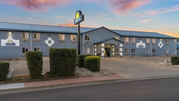 A Days Inn by Wyndham hotel with a simple, functional design, featuring a large parking lot and a clear sky.