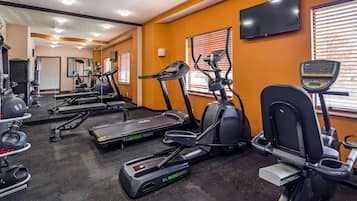 Uma academia com esteiras, elípticos e equipamentos de musculação.