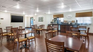A spacious dining area with wooden tables and chairs, a kitchen counter with appliances, and a large blackboard on the wall. - Sleep Inn Henderson-Evansville South (Henderson)