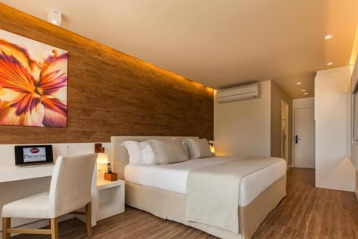 A modern hotel room with a bed, a desk, and a chair.