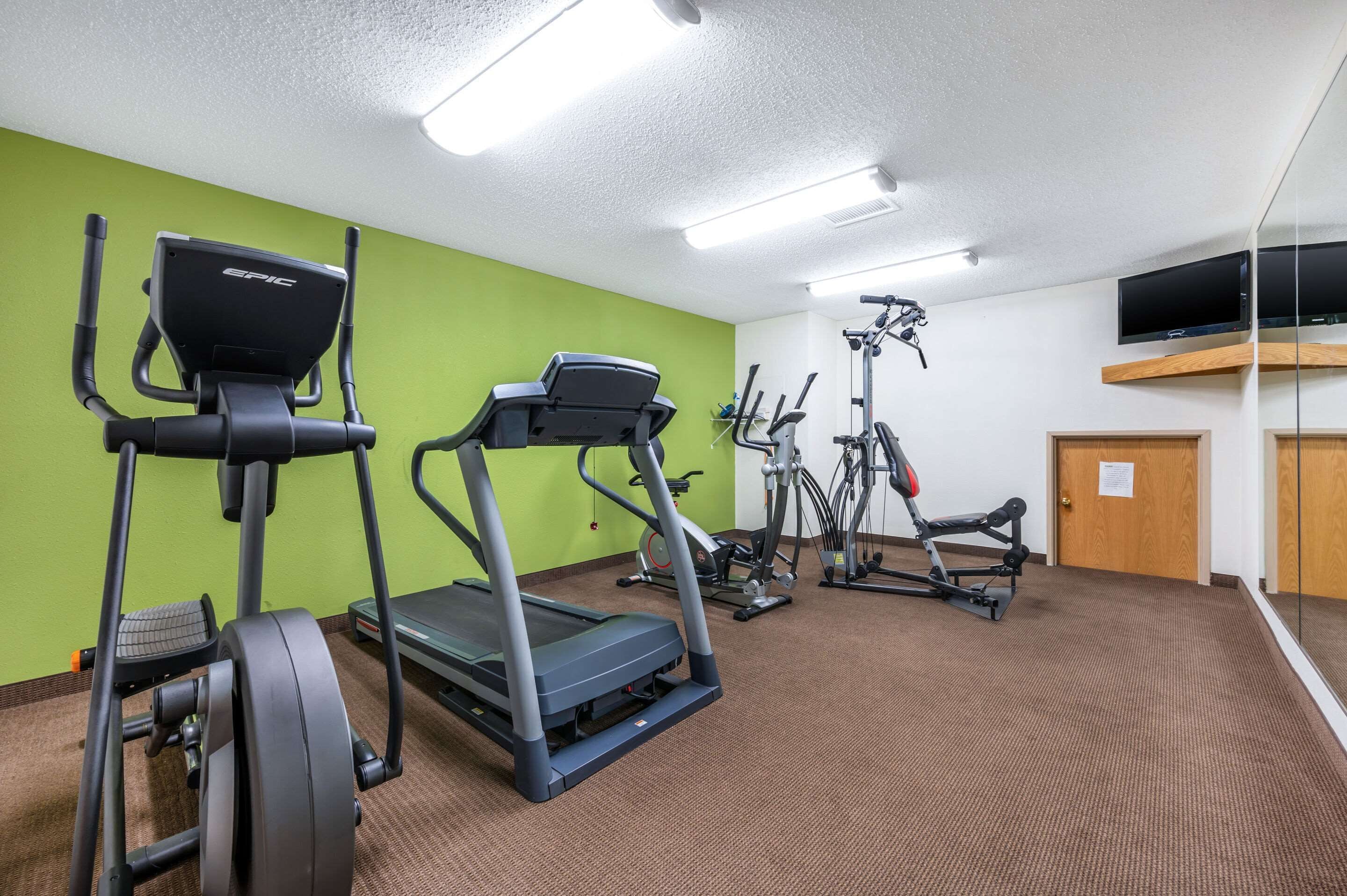 Une salle de sport équipée de tapis de course, de vélos elliptiques et d'appareils de musculation.