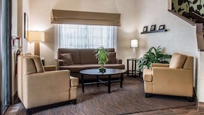 A living room with a sofa, two armchairs, a coffee table, and a potted plant.