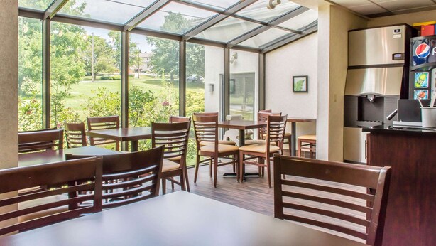 A restaurant with a glass enclosure, wooden furniture, and a refrigerator with a Pepsi logo.