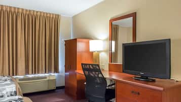 Habitación de hotel con cama, escritorio con computadora, silla, televisor y aire acondicionado.