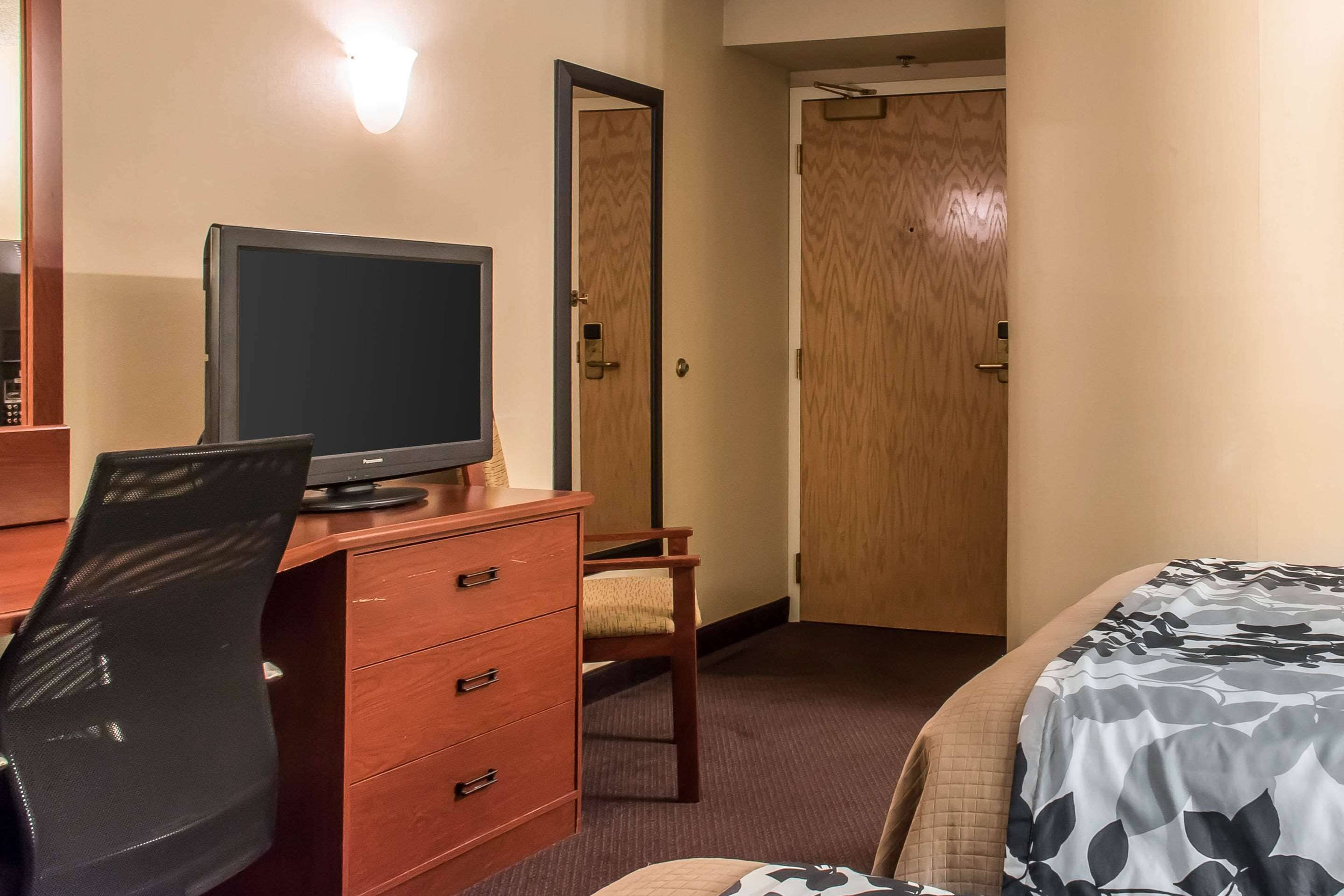 Una habitación de hotel con escritorio, una silla, una cama y un televisor.