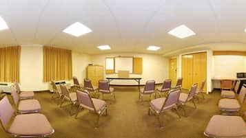 A conference room with a large table, multiple chairs, a whiteboard, and a television.