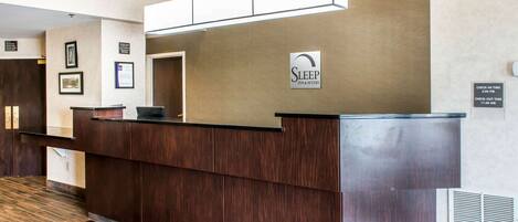 A reception desk with a sign for Sleep Inn & Suites, a check-in time of 3:00 PM, and a check-out time of 11:00 AM.