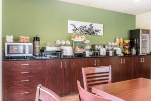 A kitchen with a microwave, coffee maker, and various appliances. There are wooden cabinets and a dining table with chairs.