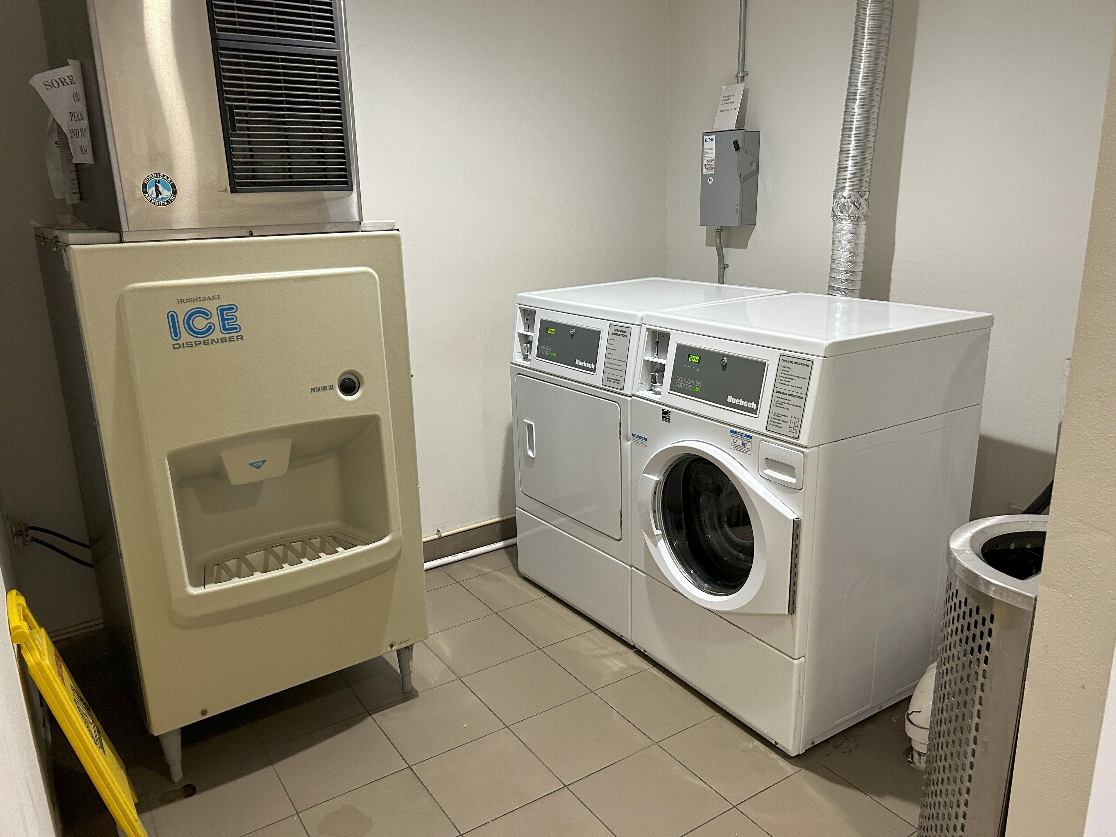 Un cuarto de lavandería con dispensador de hielo y lavadora de carga frontal.