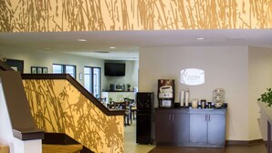 Un vestíbulo de hotel con una escalera que conduce a un comedor, una cocina al fondo y una estación de café.