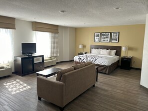 A hotel room with a bed, a TV, a desk, a chair, and a lamp.
