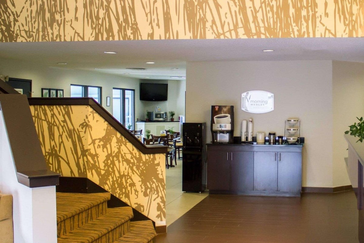 A hotel lobby with a staircase, a reception area, and a kitchen in the background.