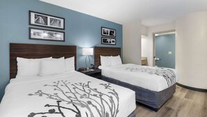 A hotel room with two beds, a nightstand with a lamp, and framed pictures on the wall. - Sleep Inn Mt. Pleasant - Charleston (Mount Pleasant)