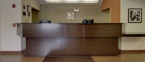 A reception desk with a 'Welcome Mount Pleasant' mat, a 'Sleep Inn' sign, and a Dell computer.