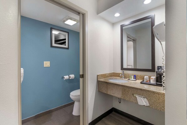 A bathroom with a blue wall, a white toilet, a sink with a mirror, and a towel rack.