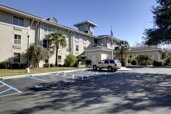 A hotel with a central courtyard, palm trees, and a flagpole. at Sleep Inn Mt. Pleasant - Charleston