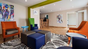 A hotel lobby with seating areas, a reception desk, and artwork on the walls.