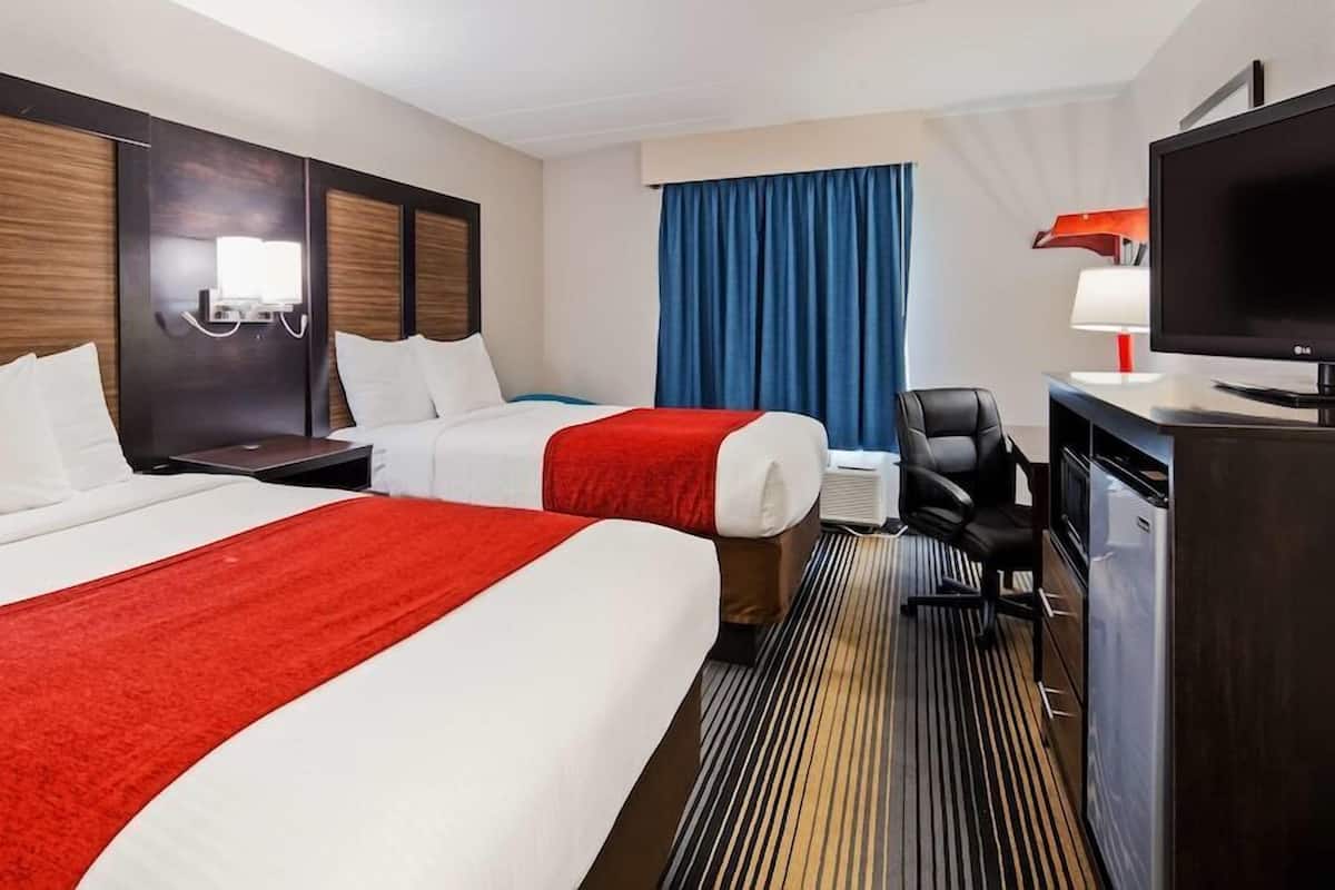 Une chambre d’hôtel avec deux lits, un bureau, une télévision et une chaise.