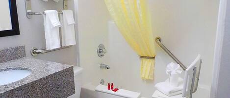 A bathroom with a granite sink, white toilet, and a shower with a yellow shower curtain.